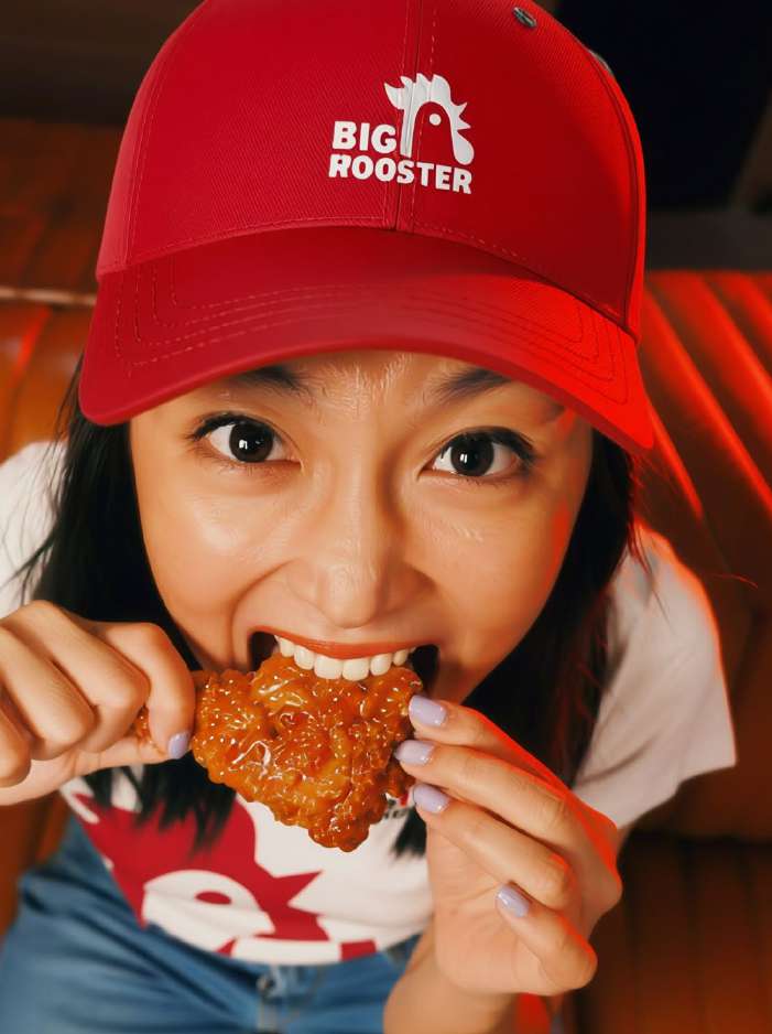 Big Rooster fan biting into chicken